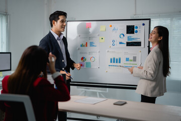 Two asian businesspeople discussing company strategy during a meeting in a modern office, using a...