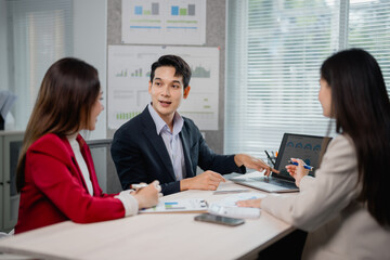 Asian businesspeople engaging in discussion and brainstorming around a project, analyzing charts...
