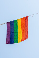 Rainbow flag on a string against a blue sky. LGBT symbol.