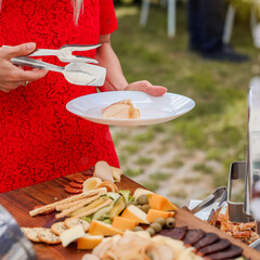 Serving cheese, cured meats, and olives from a charcuterie board at an outdoor event. A plate held...