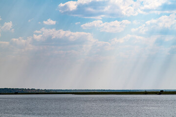 idyllic landscape with lake, grassland, cloud and sunbeams