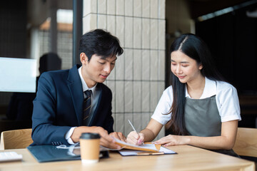 Document Signing and Collaboration. Young professionals completing paperwork in a modern office...