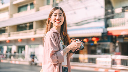 Asian woman traveller using digital camera travel at local city street market Yaowarat Bangkok, Thailand