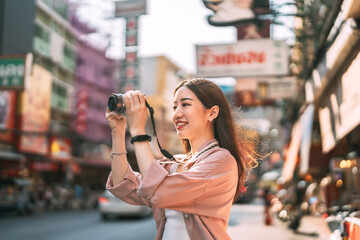 Asian woman traveller using digital camera travel at local city street market Yaowarat Bangkok, Thailand