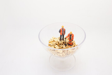 Miniature Workers Inspecting Gold Bars in a Clear Glass Bowl