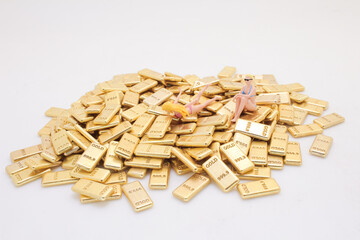 Figures on Pile of Gold Bars Depicting Wealth and Luxury