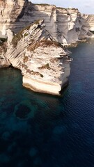 Falaises blanches et grain de sable de Bonifacio plongeant dans la mer m&eacute;diterran&eacute;en, photographi&eacute;es en hauteur par une lumi&egrave;re de fin d&rsquo;apr&egrave;s-midi.