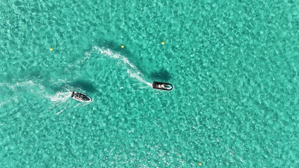 Deux jets ski vus du ciel dans les eaux claires de la baie de Santa Giulia, tra&ccedil;ant des sillages blancs sur fond turquoise.