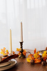 Elegant autumn table setting with candles and seasonal decor in natural light