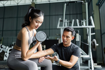 Personal Trainer Coaching Female Client in Gym. Strength Training and Fitness Guidance.
