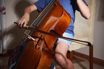 Close-Up of a Young Musician Playing a Cello in a Warm Indoors Setting