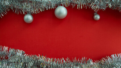 Christmas background with copy space in the center. Christmas balls and tinsel on a red background.