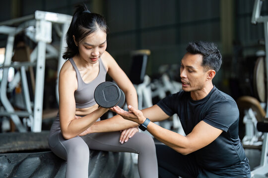 Personal Trainer Guiding Female Client with Dumbbell. Focus on Strength and Fitness. - Powered by Adobe