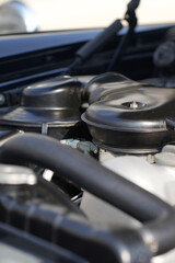 The engine and battery compartment of a classic car, with its detailed mechanical and electrical components, the vintage engineering powering the vehicle.