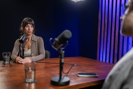 Woman engaged in podcast discussion with man