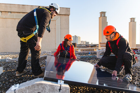 Workers installing solar panels on a rooftop