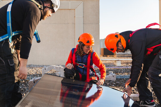 Workers installing rooftop solar panels in daylight