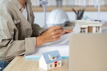 Architect working on building plans with model house