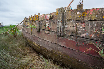Abandoned Boats – Coastal Landscape. A collection of weathered sailboats rests on a muddy tidal...