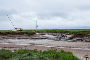 Abandoned vessel – a lonely boat marooned in a desolate tidal estuary. The image evokes themes of...
