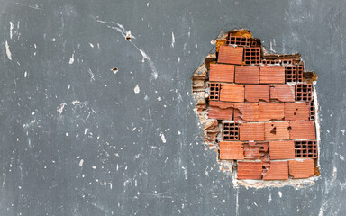 a damaged wall with peeling plaster and exposed bricks
