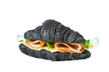 Black croissant sandwich with cheese, ham and pea microgreens isolated on white.