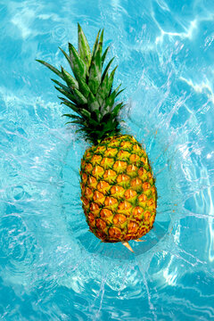 Pineapple splash in blue water captured from top view