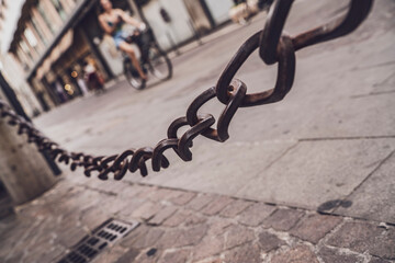 Close up of rusty metal chain stretching across cobblestone street