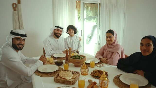 Muslim family sharing traditional meal, parents and son connecting through joyful dining experience in bright, modern home interior, embodying familial warmth and cultural togetherness