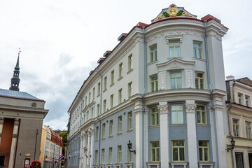 Obraz premium Corner view of a historic building with grey and white façade, yellow windows, and a naval emblem near Freedom Square in Tallinn, Estonia.