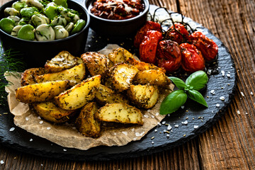 Boiled broad bean with roasted potatoes and cherry tomatoes with tomato pesto on wooden table