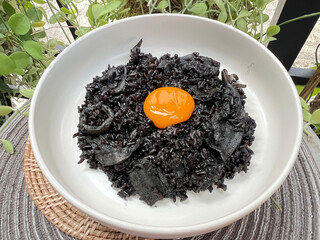 Black squid ink risotto with squid and yolk egg on top.