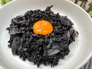 Black squid ink risotto with squid and yolk egg on top.