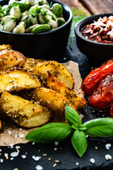Boiled broad bean with roasted potatoes and cherry tomatoes with tomato pesto on wooden table