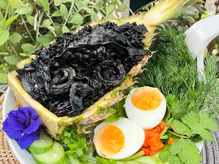 Black squid ink risotto with squid and boiled egg in the pineapple