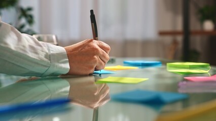 Person Writing on Colorful Sticky Notes on Glass Desk