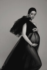 beautiful pregnant woman with dark hair in luxurious evening tulle black dress