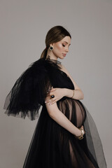 beautiful pregnant woman with dark hair in luxurious evening tulle black dress