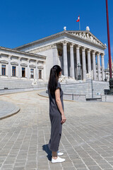 Female tourist looks at the Austrian Parliament building. View from the back. Austria, Vienna