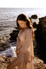 beautiful woman with dark hair in elegant beach clothes posing on the beach