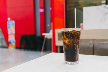 Refreshing Glass of Carbonated Soft Drink on a White Table in a Vibrant Modern Cafe Environment