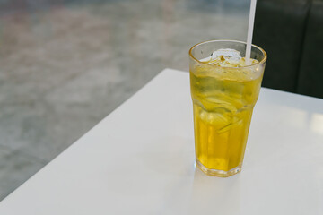 Refreshing glass of iced tea with lemon and ice on a white table in a modern cafe setting