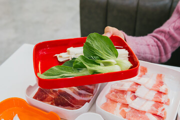 Fresh Ingredients for Hot Pot Meal with Meat and Green Vegetables in Restaurant Setting