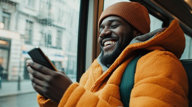 A smiling black man in a colorful jacket laughing while on public transportation.