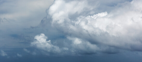A serene panoramic view of white fluffy clouds stretching across a clear blue sky