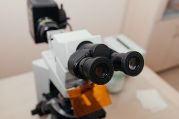 Black medical microscope in clinical office setting with diagnostic equipment