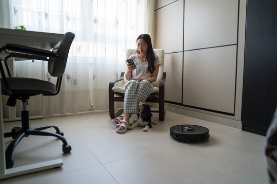 Woman with dog using phone in modern home office