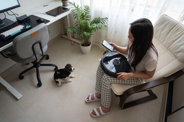 Woman with robot vacuum and dog in home office