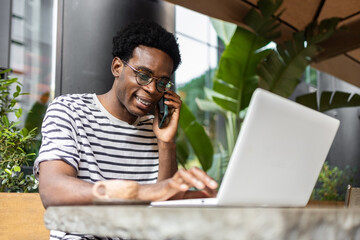 Man using laptop and phone in a cafe setting