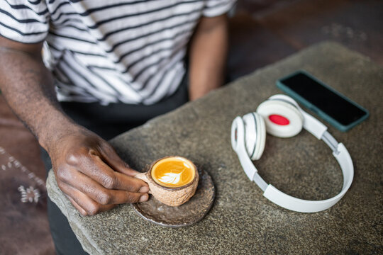 Man enjoying coffee in a cafe with headphones nearby